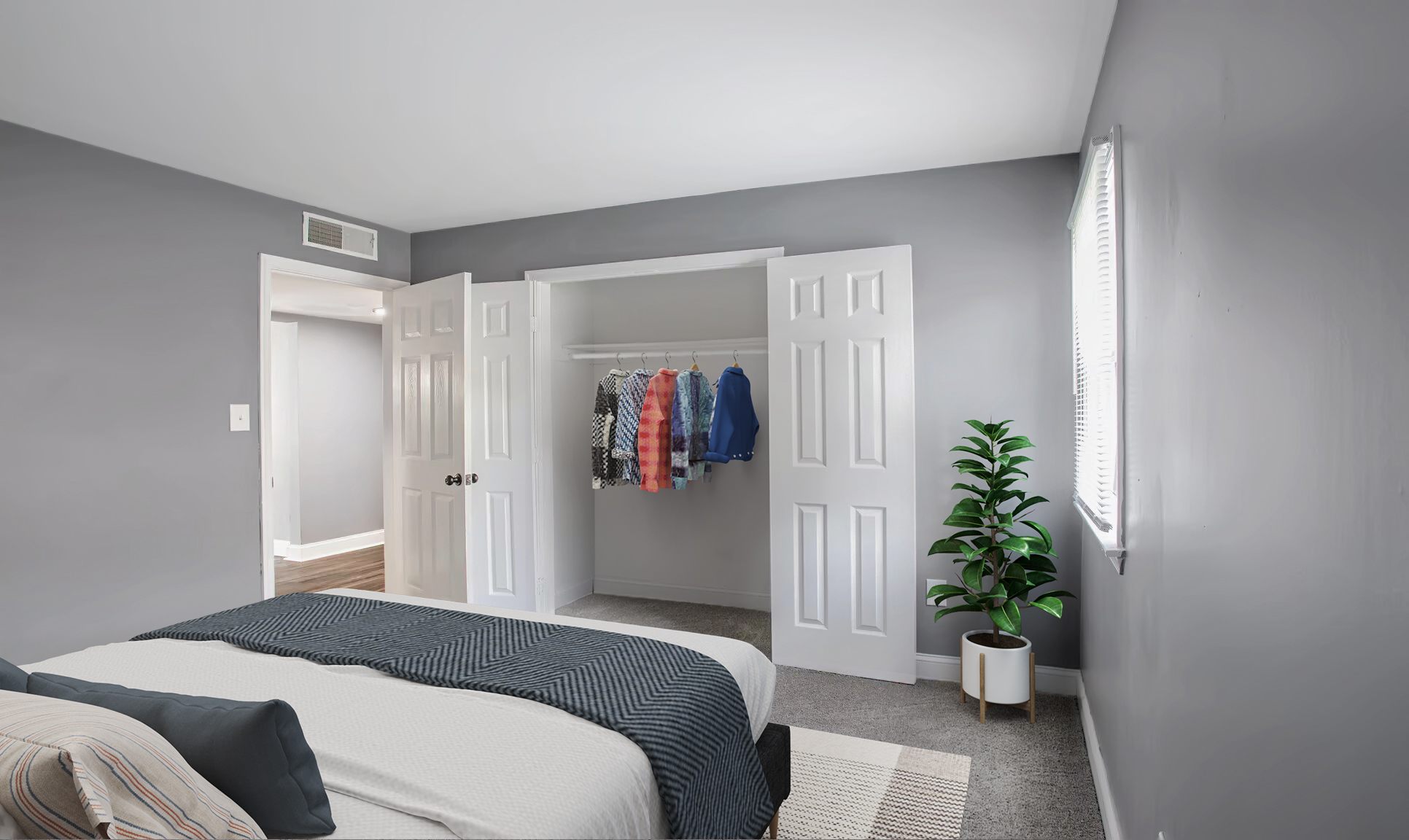 A bedroom with a bed, a wardrobe, and a plant.